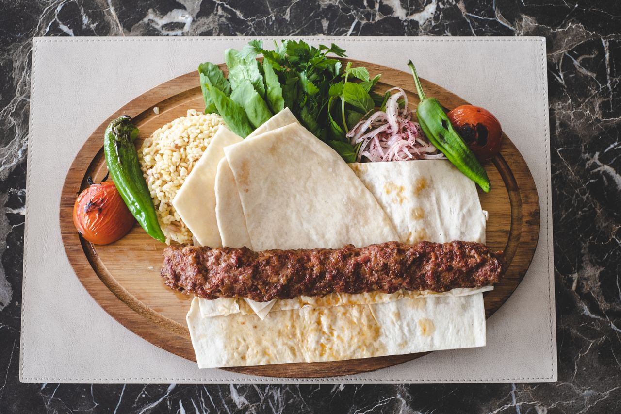 Odun ateşinde pişen şiş kebap, közlenmiş domates ve biberle hazırlanmış geleneksel servis